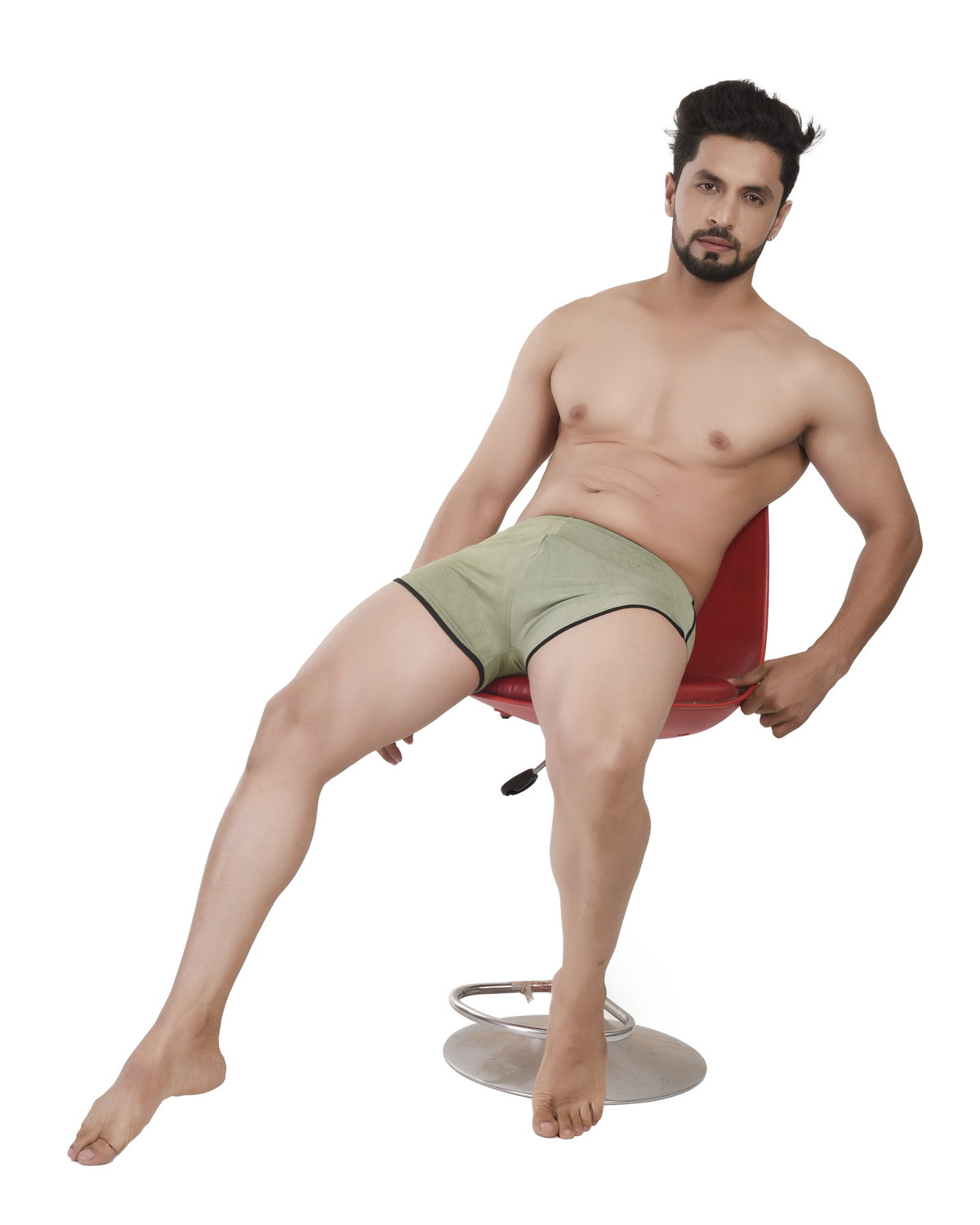 Man sitting on a red chair wearing green boxer briefs against a white background