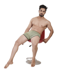 Man sitting on a red chair wearing green boxer briefs against a white background